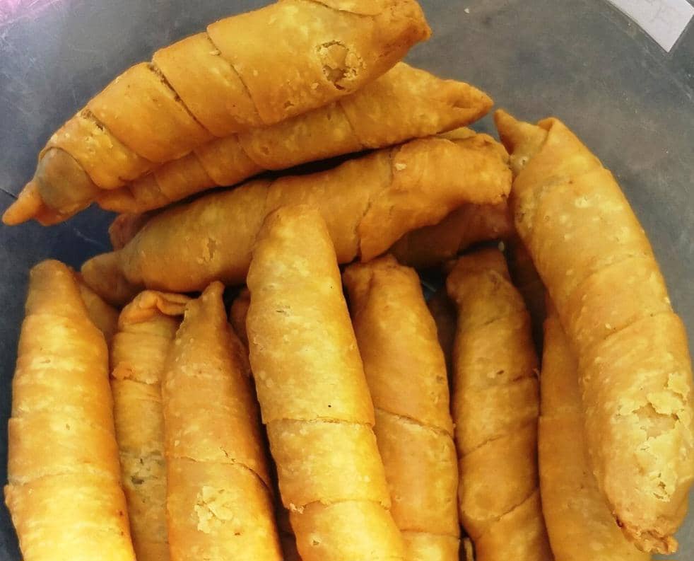 Pisang molen goreng berwarna cokelat keemasan dengan kulit renyah tersusun di atas piring sebagai camilan manis.