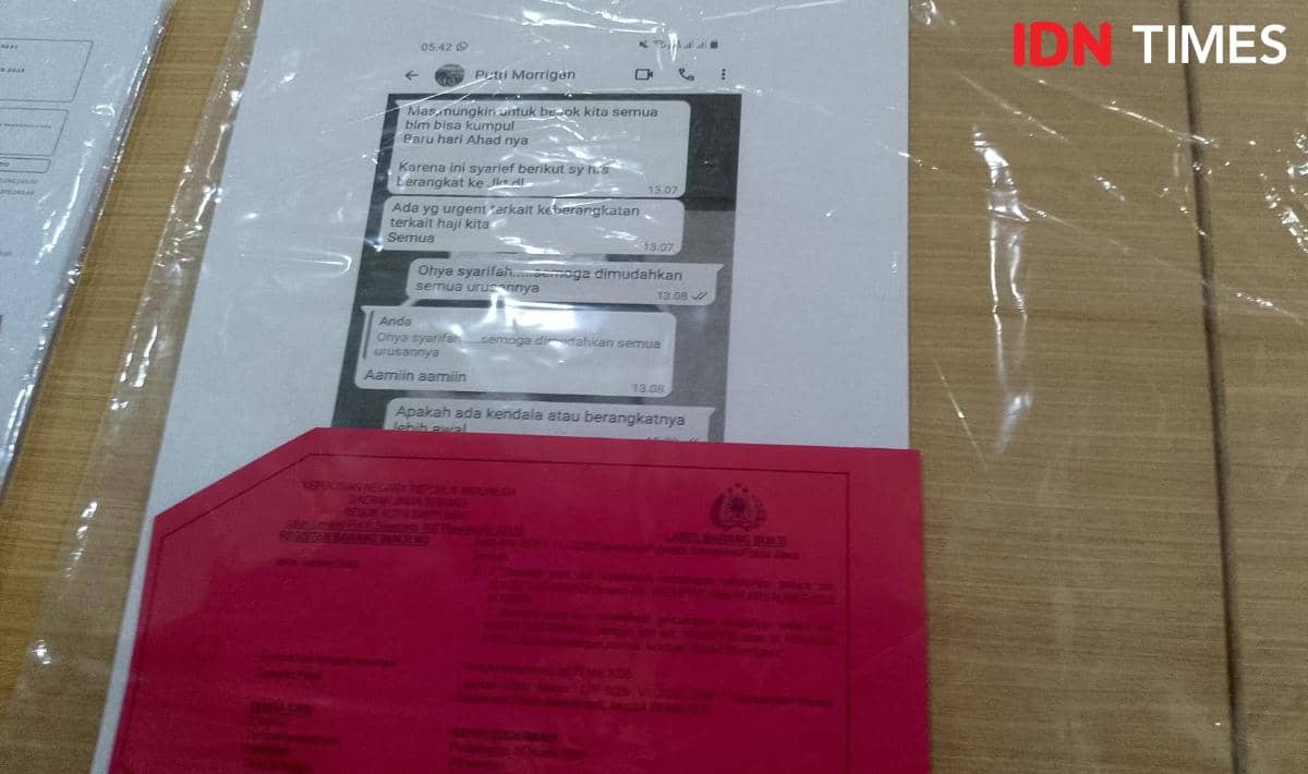 Barang bukti berupa tangkapan layar percakapan pesan dan dokumen berwarna merah yang ditampilkan di meja oleh Polresta Banyumas.