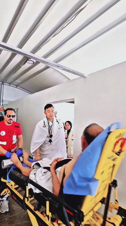 Seorang dokter dan tim medis membantu jamaah haji yang terbaring di tandu di koridor fasilitas kesehatan dengan suasana siaga.