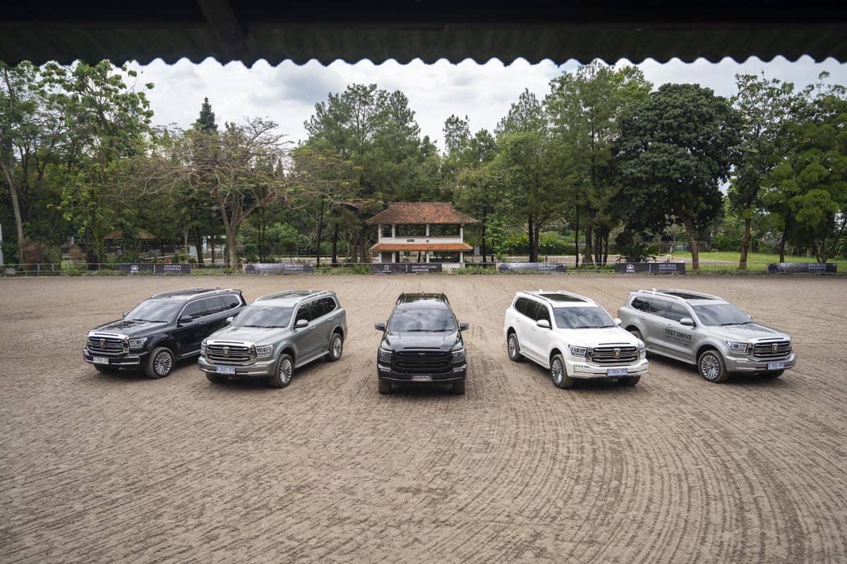 Lima unit SUV GWM Tank 500 berbagai warna berjejer di area terbuka dengan latar pepohonan dan bangunan kecil di belakangnya.