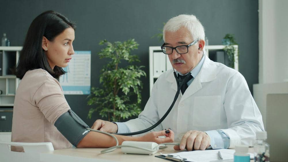 Seorang dokter sedang mengecek tekanan darah pasien