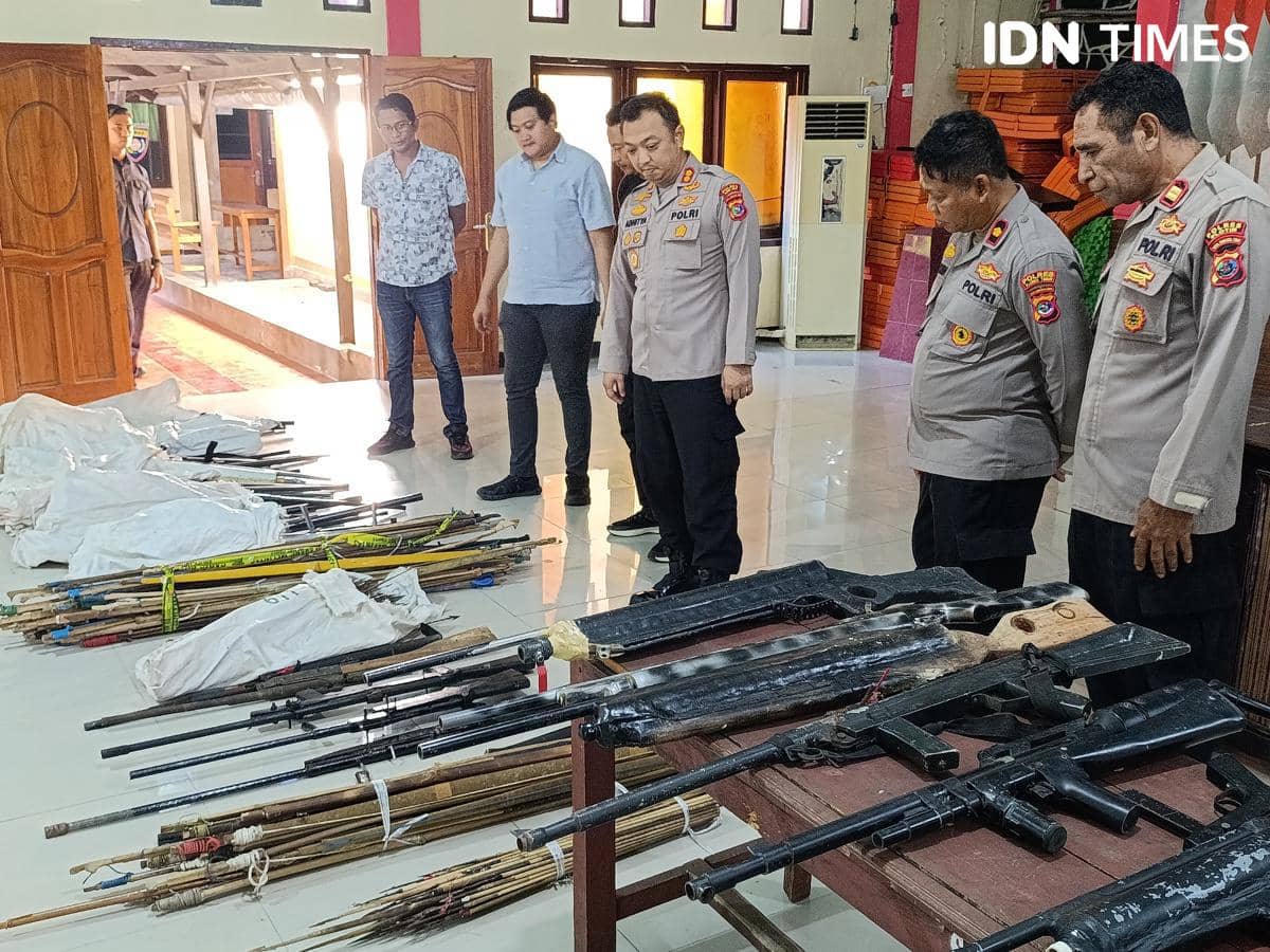 Petugas Polres Flores Timur memeriksa deretan senjata api dan senjata tajam yang diserahkan warga Adonara secara sukarela di dalam ruangan.