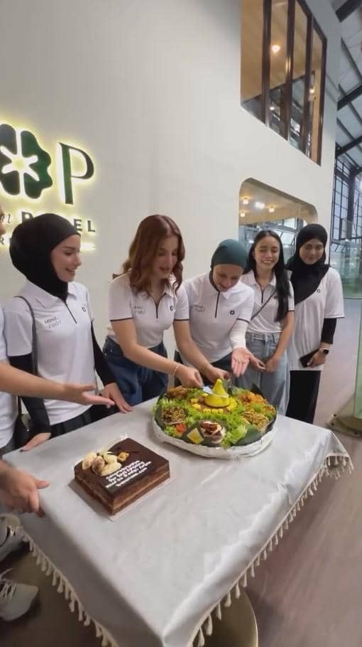 Beberapa wanita mengenakan kaus putih sedang memotong tumpeng di atas meja dalam acara syukuran di Lapangan Padel.