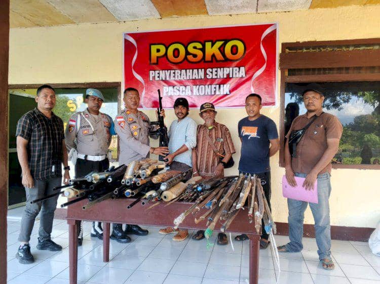 Beberapa warga dan petugas kepolisian berdiri di depan meja berisi senjata api rakitan dan senjata tajam di posko penyerahan pasca konflik di Adonara.