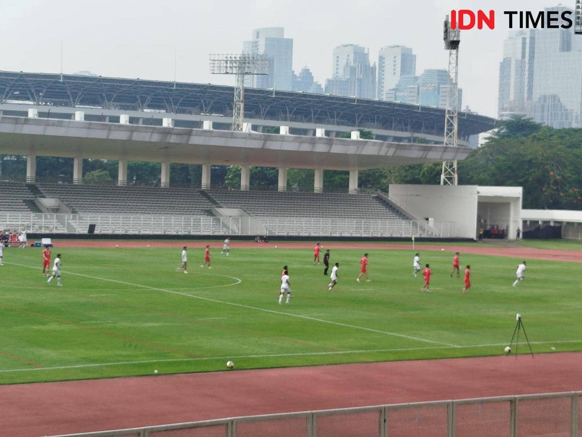 Pemain Timnas Indonesia berlatih di Stadion Madya dengan latar gedung pencakar langit Jakarta di bawah langit cerah.