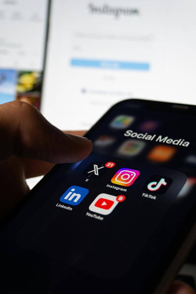 Seseorang menggenggam ponsel yang terpampang sosial media di layarnya.