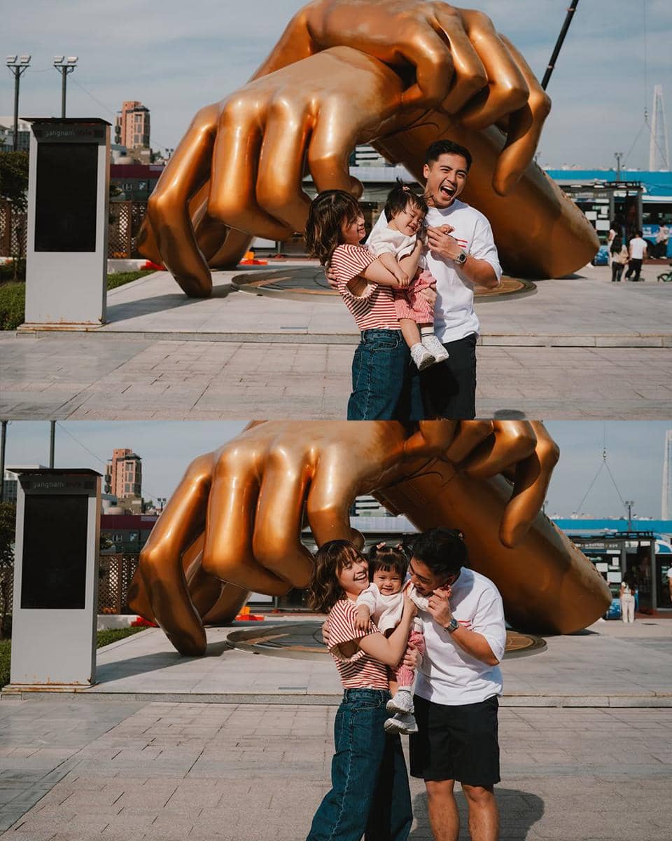 Sebuah keluarga berpose ceria bersama anak kecil di depan patung tangan emas besar di kawasan Gangnam, Seoul, Korea Selatan.