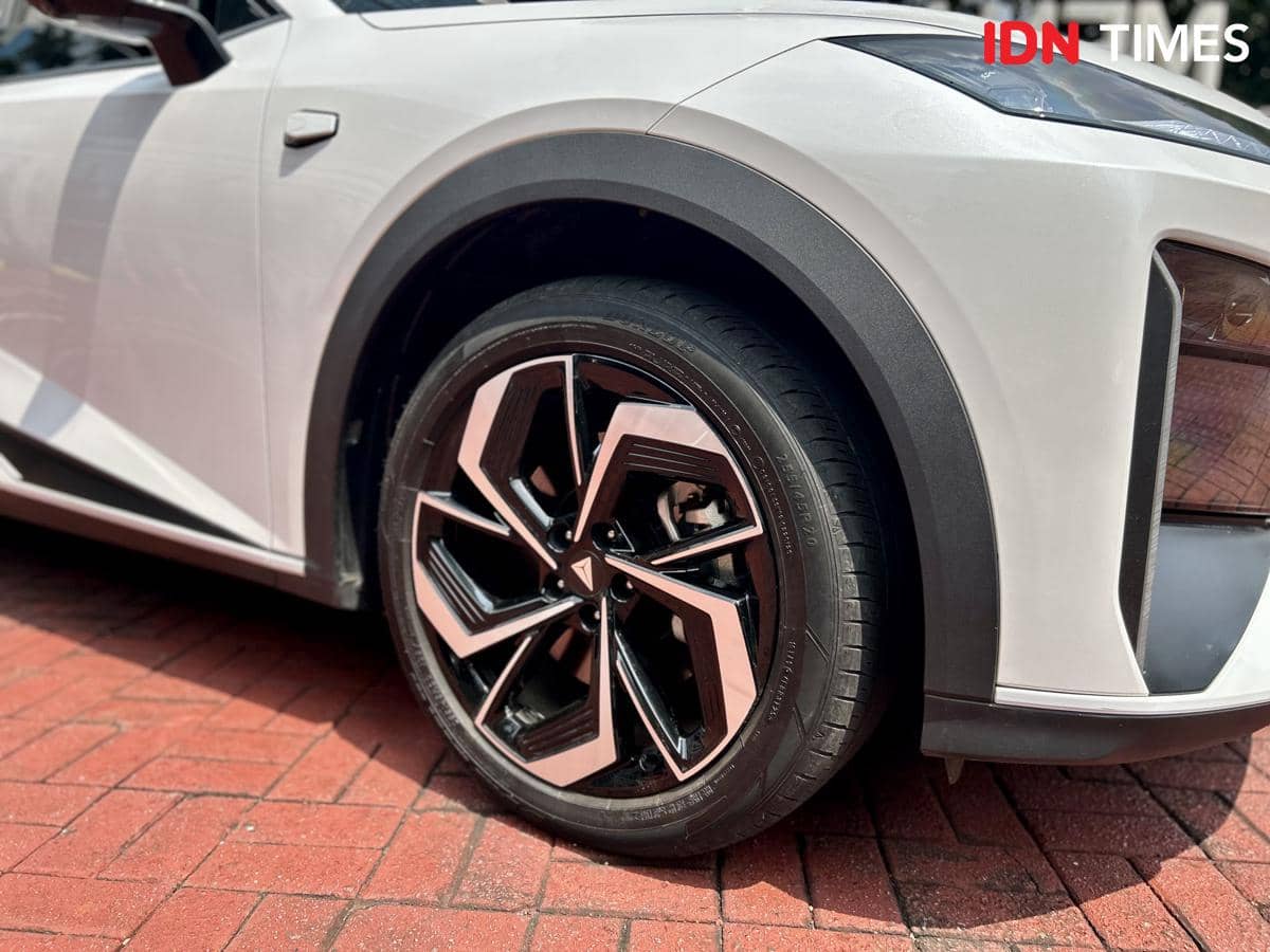 Roda mobil berdiameter 20 inci dengan desain pelek modern berwarna hitam dan aksen perak, terpasang pada bodi mobil berwarna putih.