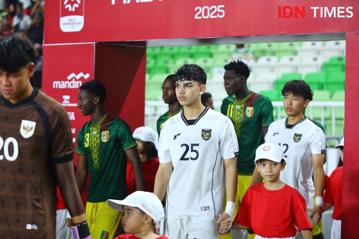 Pemain Timnas Indonesia U-19 mengenakan seragam putih berjalan memasuki lapangan bersama pemain lawan dan anak pendamping sebelum pertandingan.