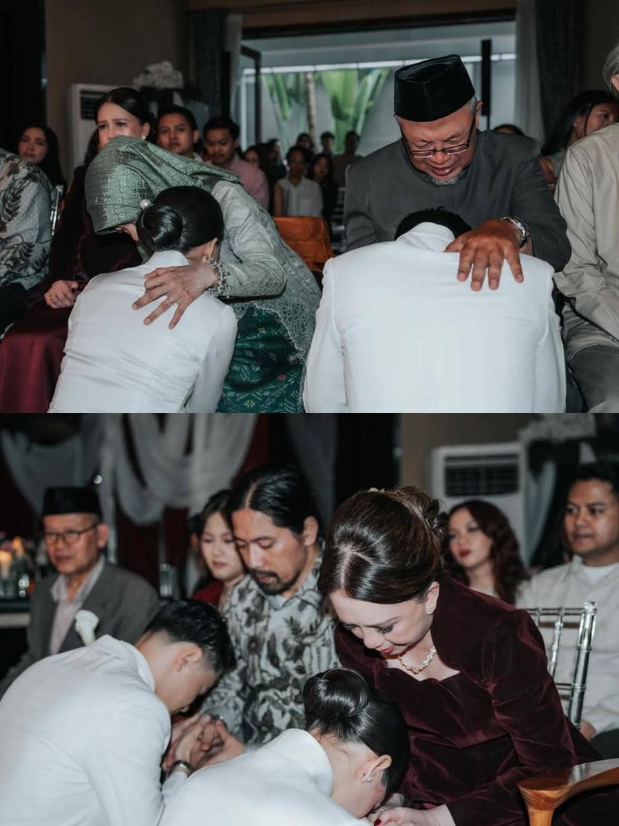 Pasangan pengantin mengenakan busana putih bersimpuh dan mencium tangan orang tua dalam prosesi pernikahan yang khidmat di hadapan keluarga.