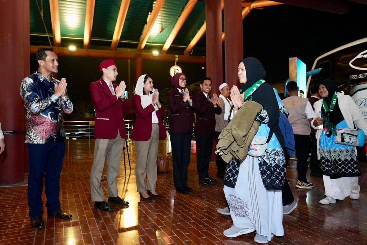 Petugas bandara menyambut jemaah haji yang tiba di Bandara Soekarno-Hatta dengan salam hangat pada malam hari.