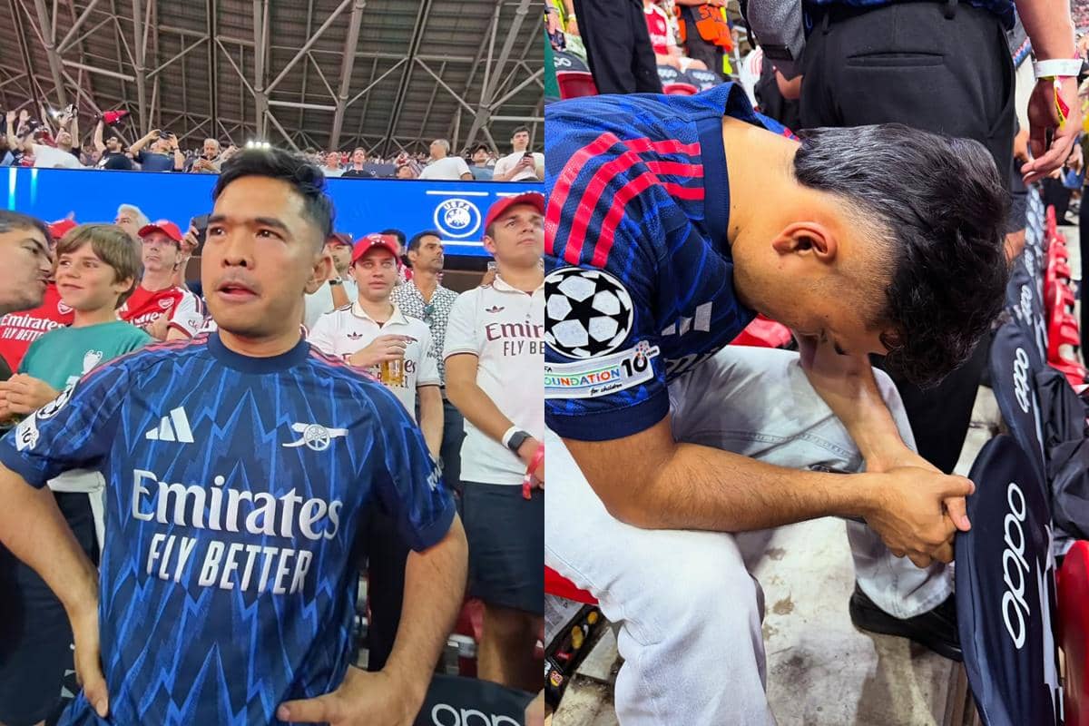 Seorang pria mengenakan jersey Arsenal menyaksikan final Liga Champions melawan PSG di stadion yang dipenuhi penonton.
