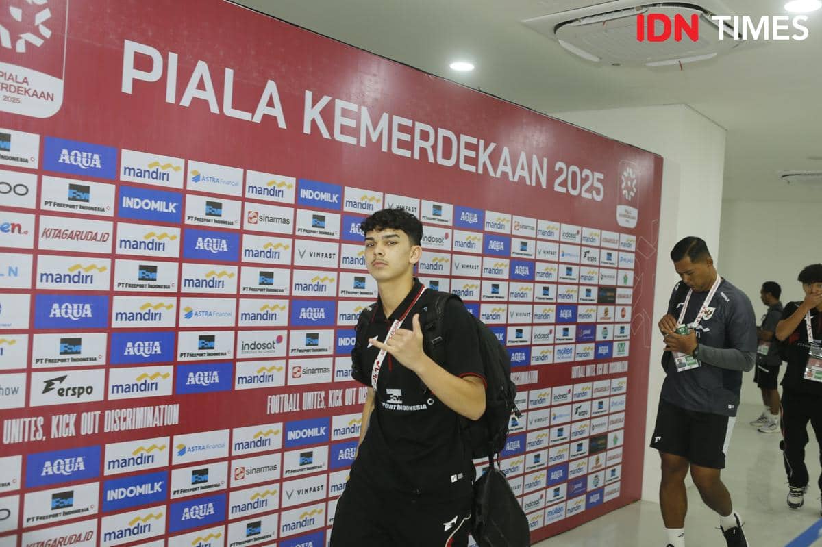 Seorang pemain Timnas Indonesia U-19 berpose di depan papan sponsor bertuliskan Piala Kemerdekaan 2025 di area dalam stadion.