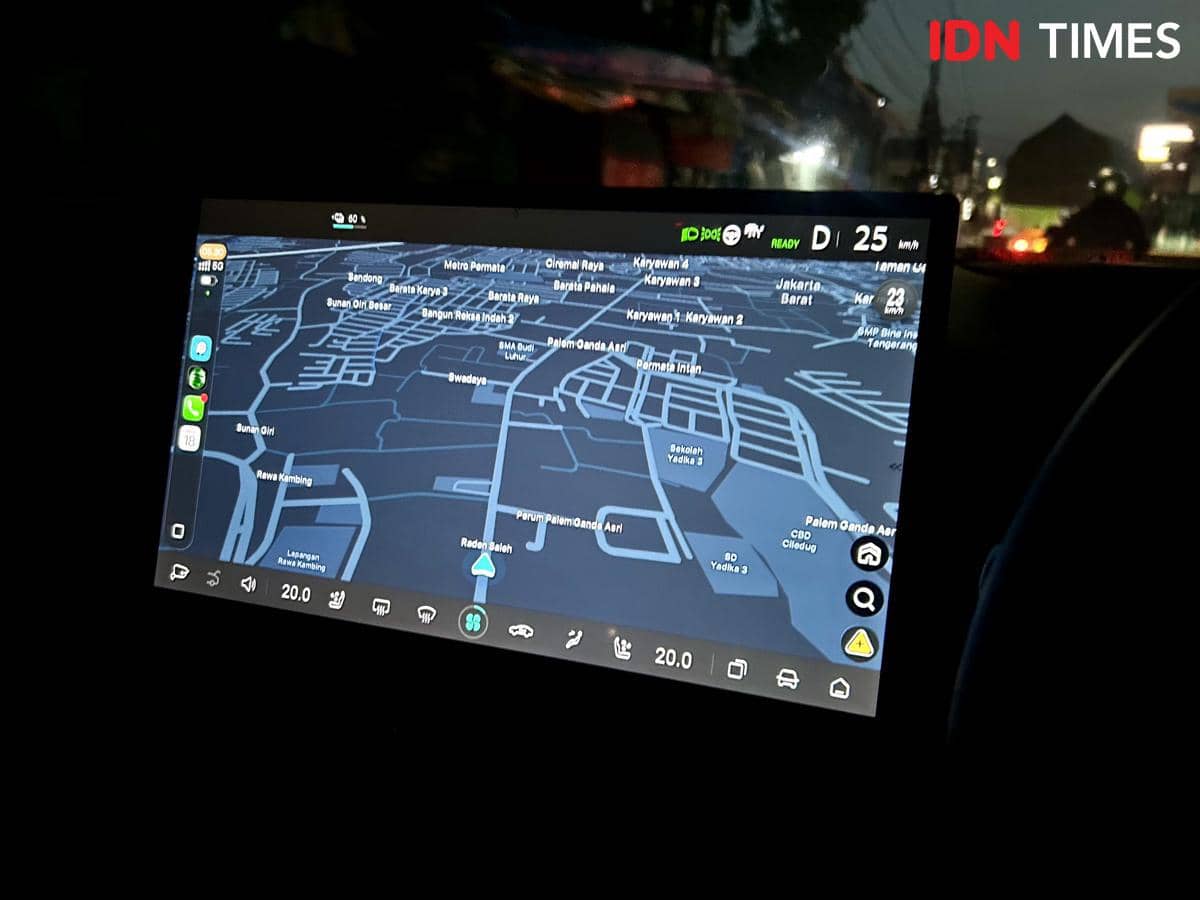 Layar head unit mobil berukuran besar menampilkan peta navigasi digital dengan konektivitas smartphone di malam hari.