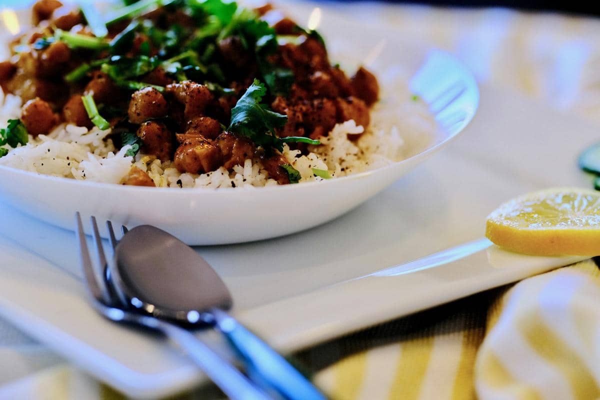 Semangkuk nasi putih dengan daging cincang berbumbu lemon dan bawang putih, dihiasi daun ketumbar segar di atas piring putih.