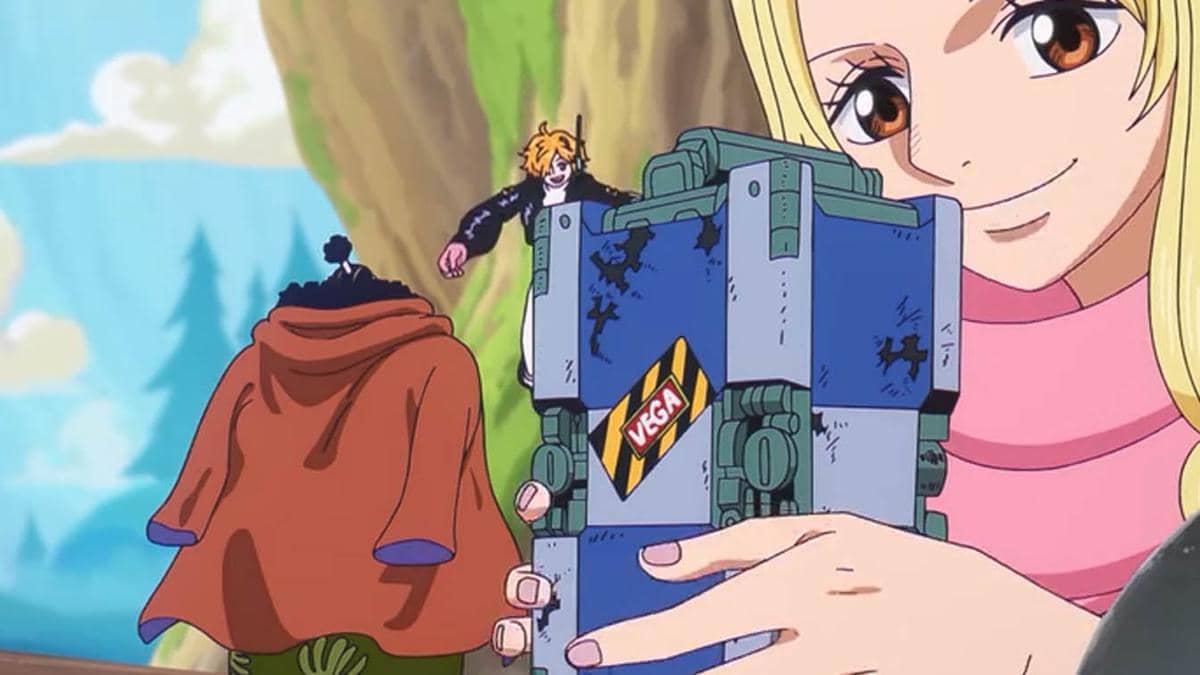 Karakter anime berambut pirang memegang kotak besi besar bertuliskan VEGA sambil tersenyum, dengan dua karakter lain di latar belakang.