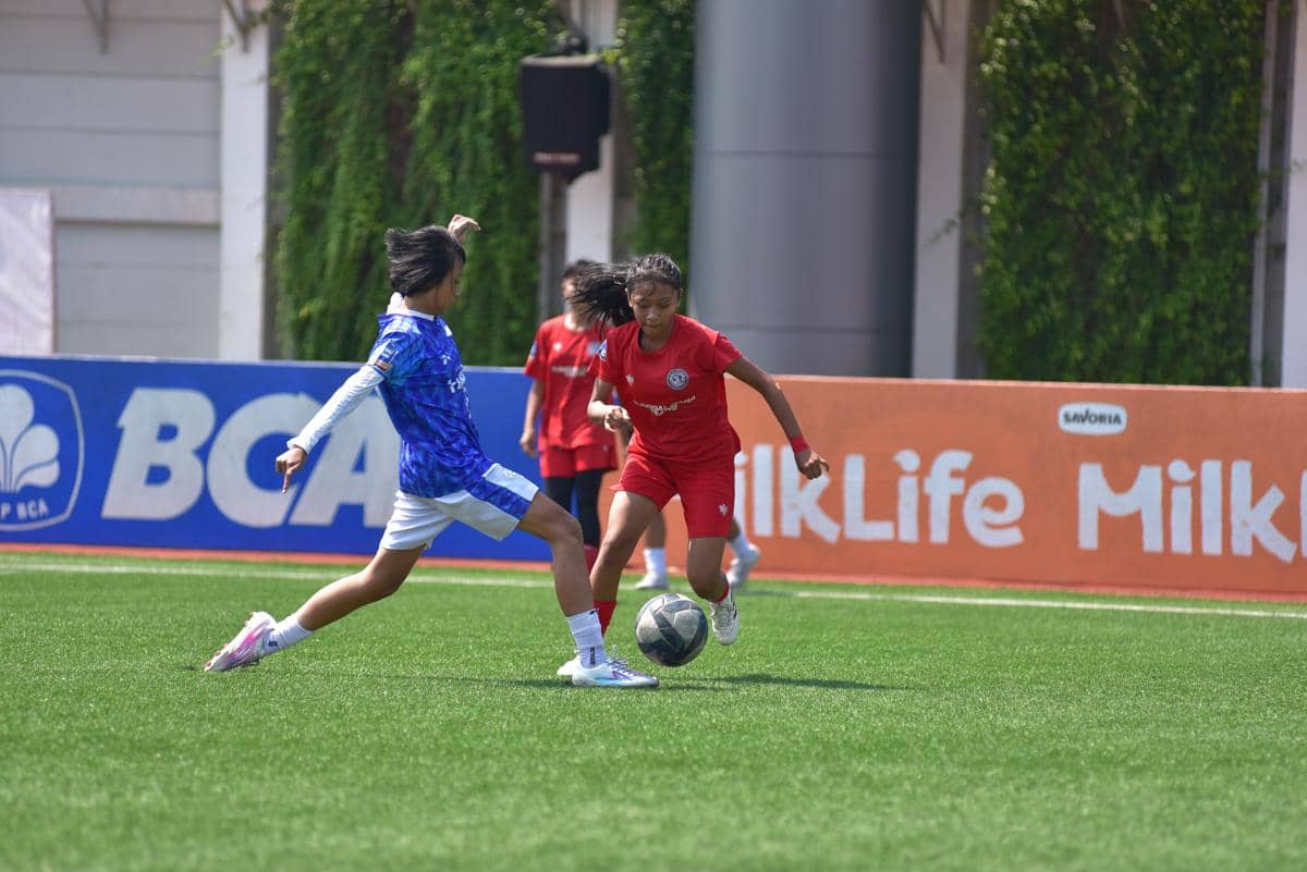 Dua pemain sepak bola perempuan berebut bola di lapangan hijau dalam pertandingan Hydroplus Soccer League Kudus.