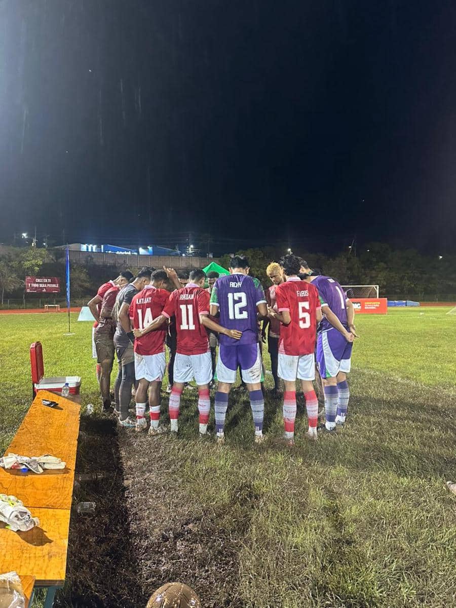 Para pemain tim sepak bola Indonesia berkumpul di tengah lapangan basah pada malam hari setelah lolos ke final IFA7 World Championship 2026.