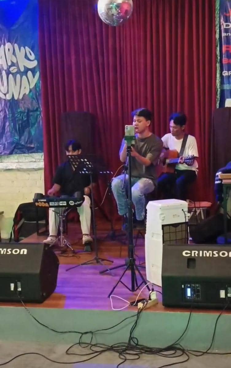 Penampilan musik live di kafe Warkomunal Bandar Lampung dengan penyanyi dan musisi memainkan gitar serta keyboard di atas panggung.