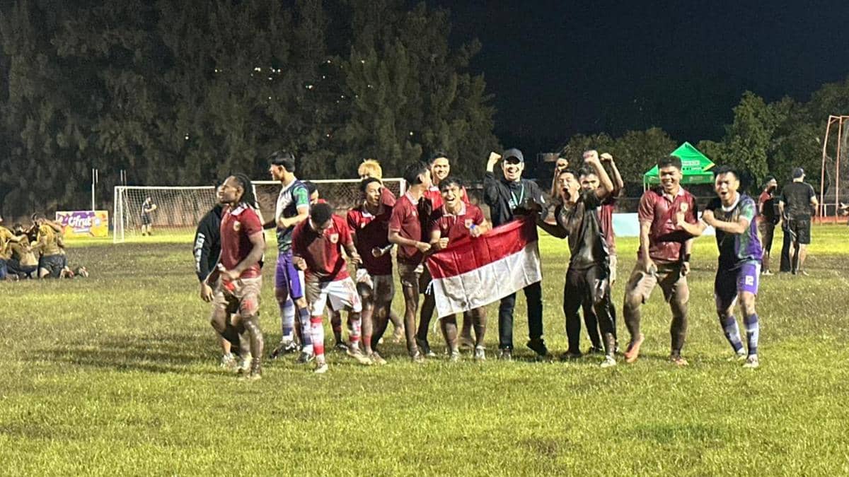 Para pemain tim Indonesia merayakan kemenangan di lapangan sepak bola malam hari sambil memegang bendera merah putih setelah lolos ke final IFA7 World Championship 2026.