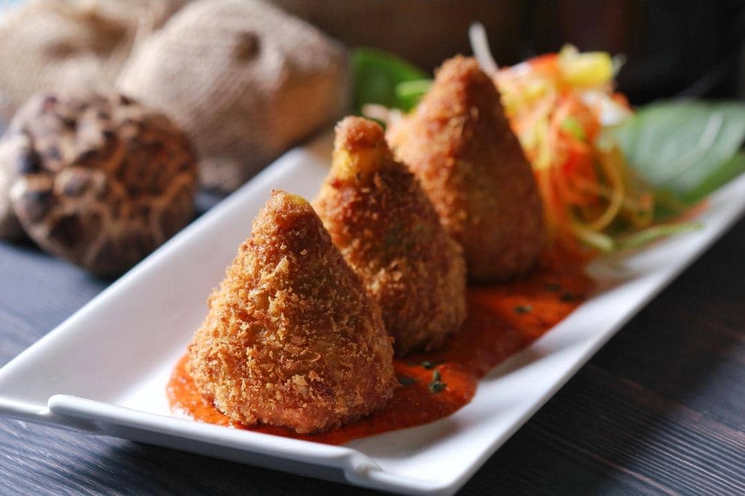 Tiga risoles goreng berwarna keemasan tersaji di atas piring putih, dengan kulit renyah dan bentuk gulungan memanjang.