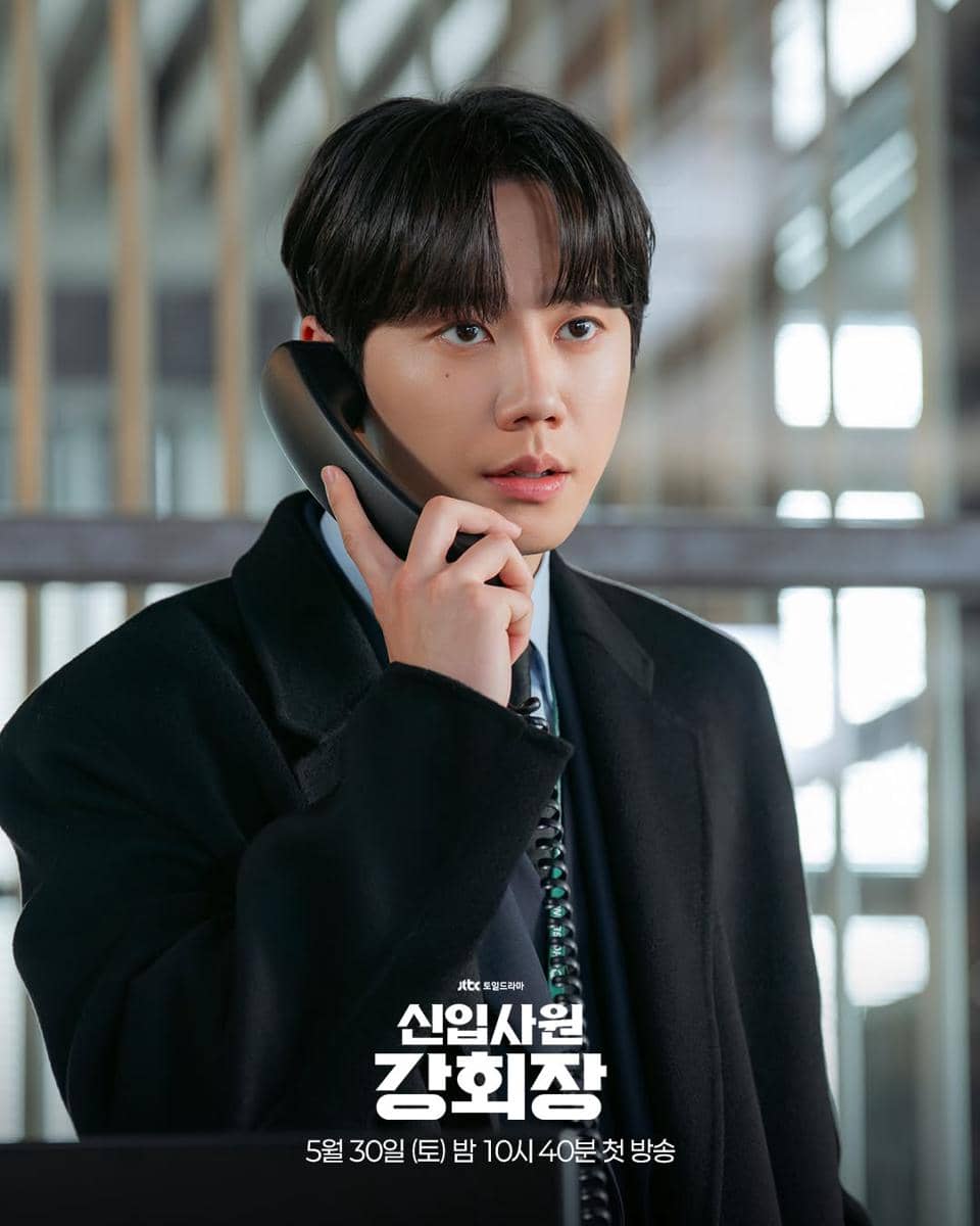 Seorang pria mengenakan jas hitam sedang berbicara di telepon di dalam gedung, dalam cuplikan drama Reborn Rookie.