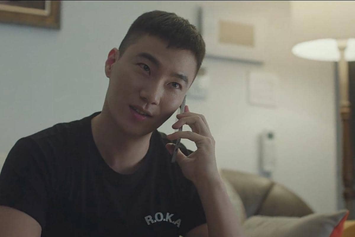 Seorang pria mengenakan kaus hitam bertuliskan R.O.K.A sedang berbicara di telepon dalam cuplikan drama The Legend of Kitchen Soldier.