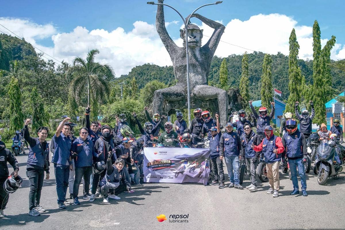 Sekelompok pengendara motor berpose di depan patung besar berbentuk kera di Sulawesi Selatan dengan latar pepohonan hijau dan langit cerah.