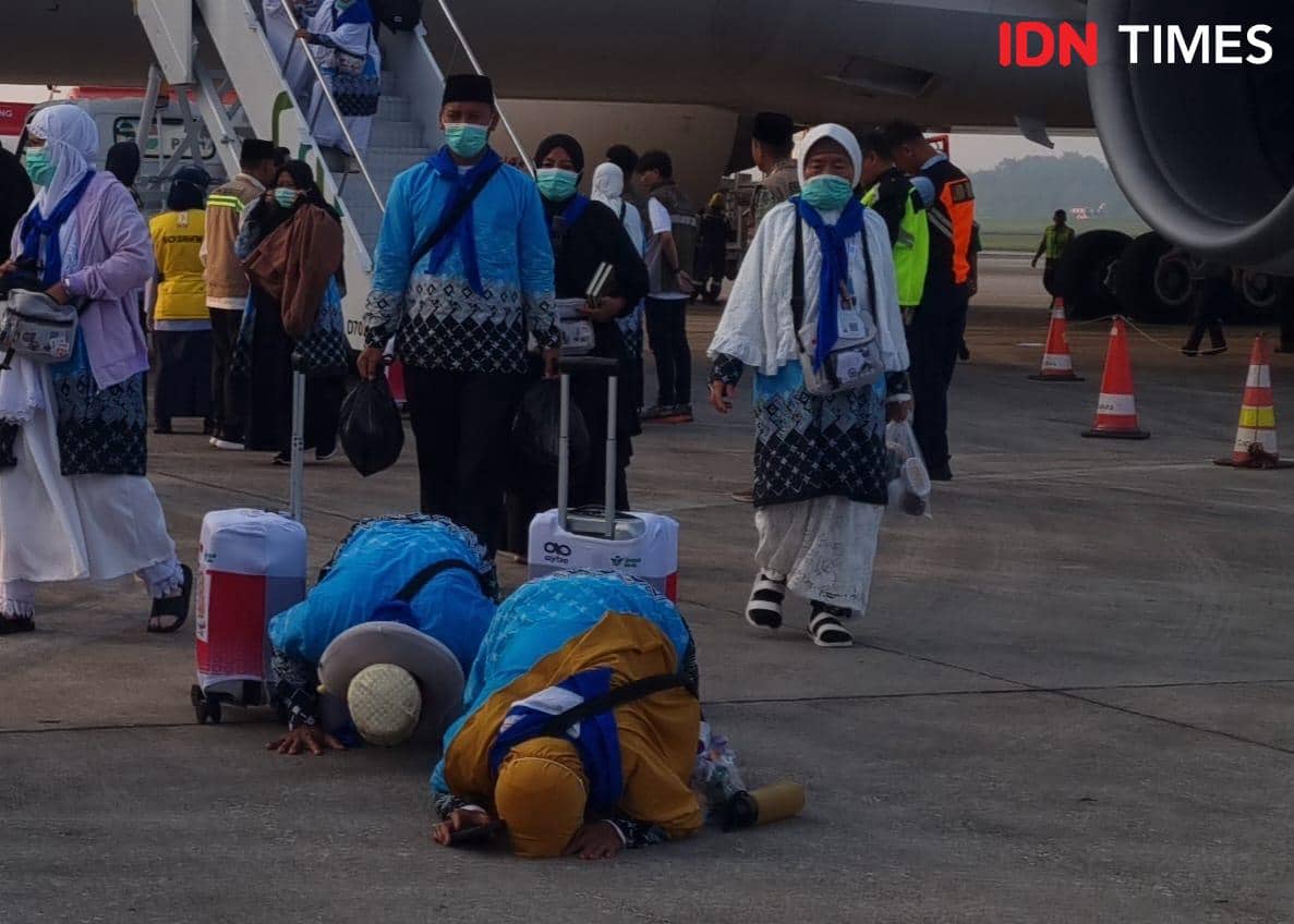 Pasutri jemaah haji melakukan sujud syukur selepas menginjakan kaki kembali di tanah kelahiran usai menjalani ibadah haji (IDN Times/Rangga Erfizal)