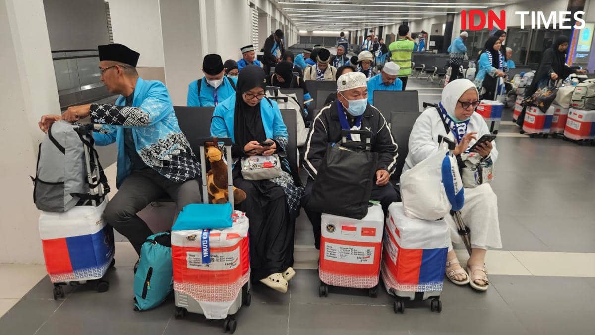 Sejumlah jemaah haji kloter pertama duduk di area kedatangan Bandara Soekarno-Hatta dengan koper dan perlengkapan haji mereka.