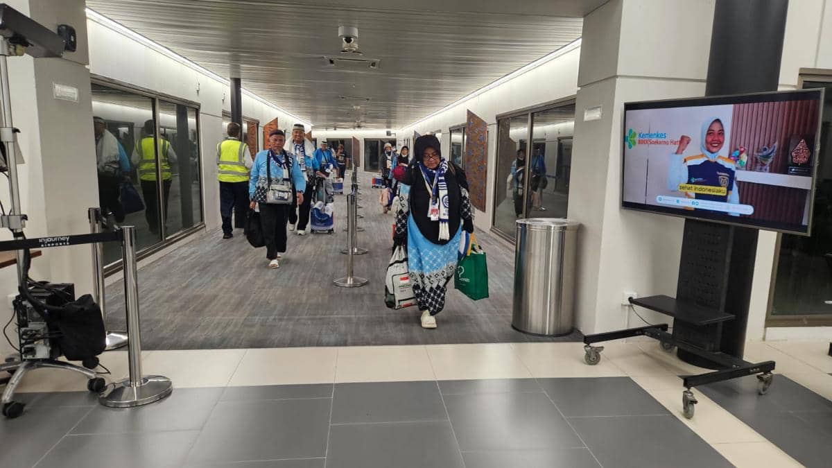 Rombongan jemaah haji mengenakan seragam biru tiba di Bandara Soekarno-Hatta sambil membawa koper dan tas setelah penerbangan pulang.