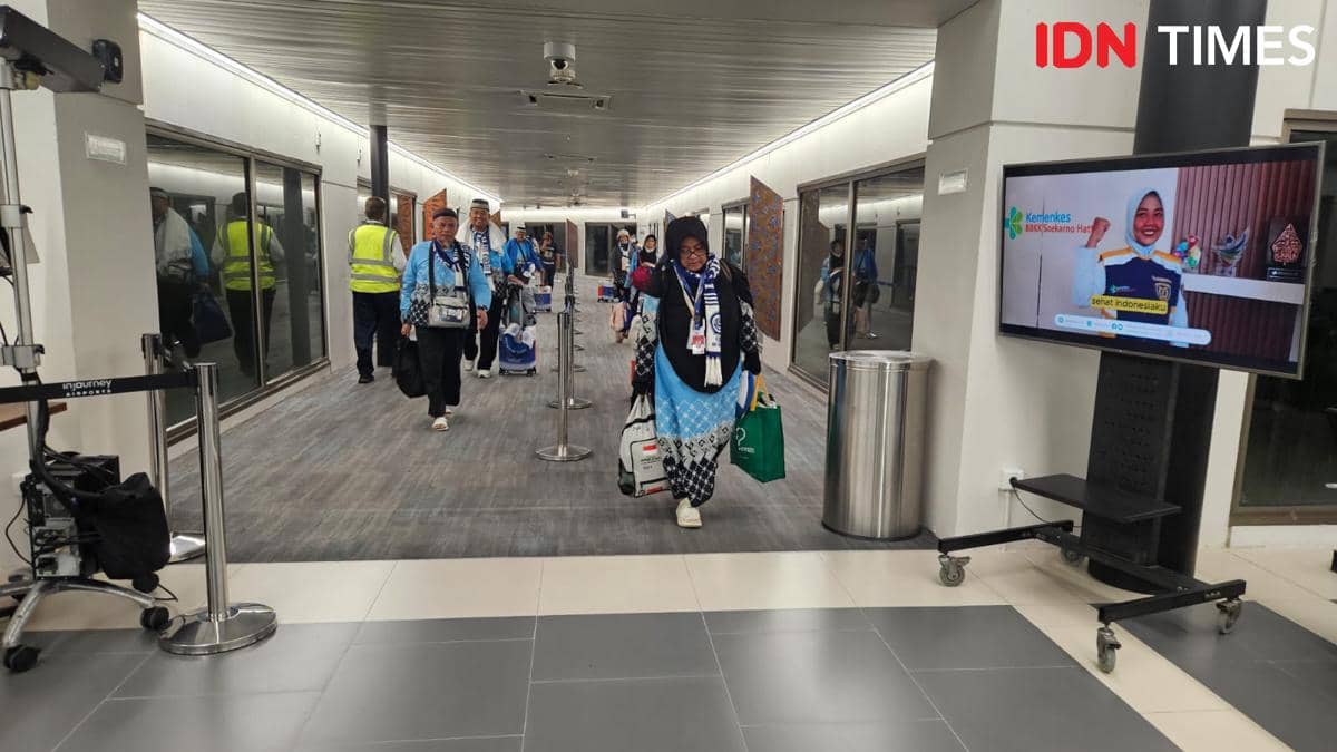 Rombongan jemaah haji mengenakan seragam biru tiba di Bandara Soekarno-Hatta sambil membawa koper dan tas setelah penerbangan pulang.