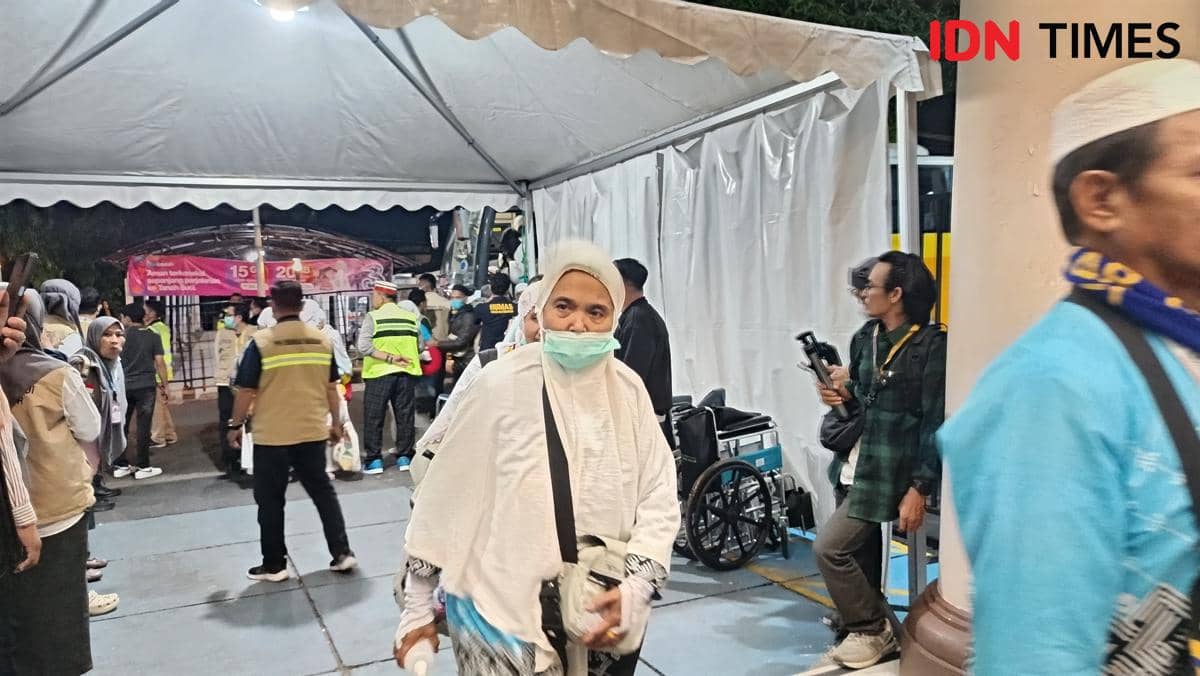 Seorang jemaah haji mengenakan pakaian ihram dan masker tiba di Asrama Haji Sudiang Makassar pada malam hari bersama rombongan Kloter 1.