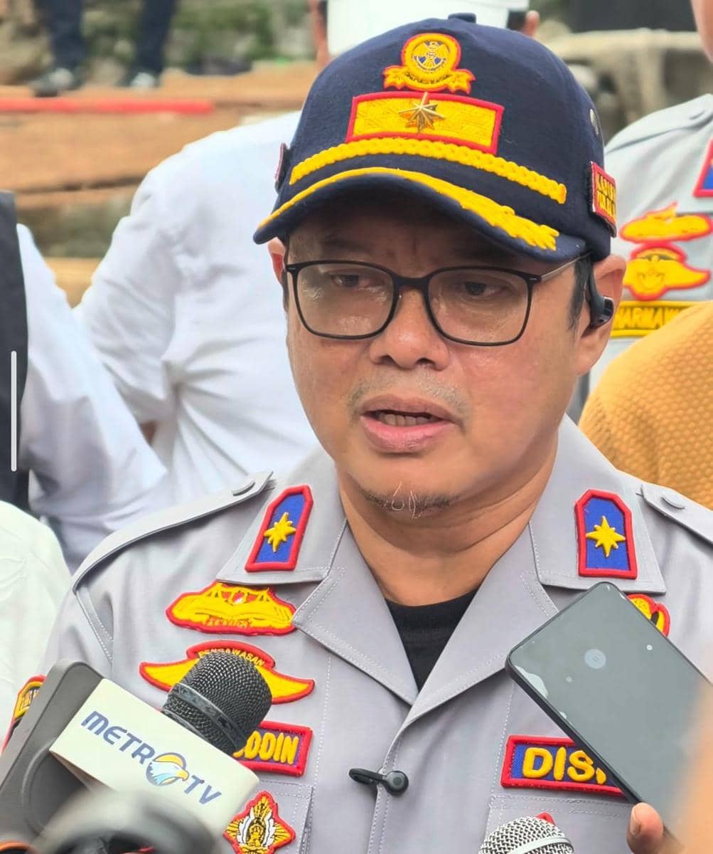 Seorang pejabat Dinas Perhubungan DKI Jakarta mengenakan seragam abu-abu dan topi dinas sedang memberikan keterangan kepada media.