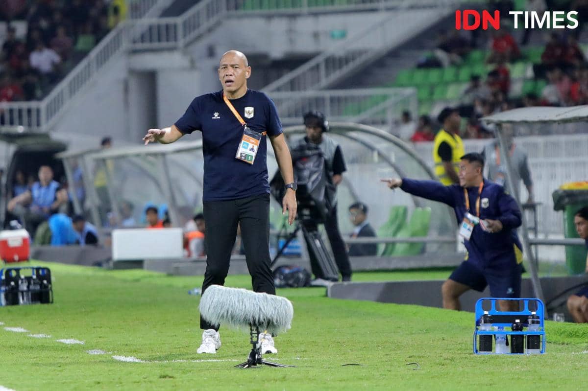 Pelatih timnas Indonesia U-19 berdiri di pinggir lapangan memberi arahan kepada pemain saat pertandingan berlangsung di stadion.