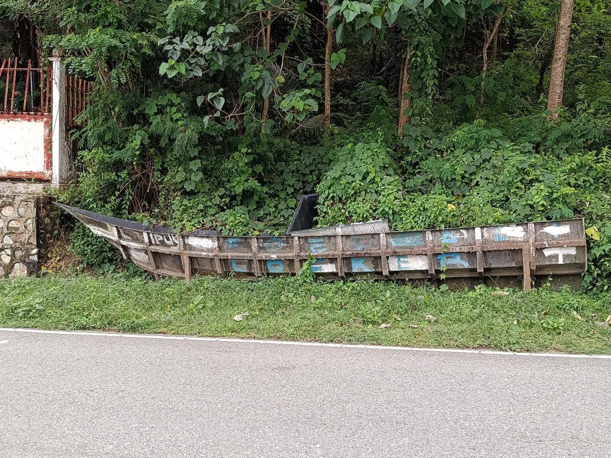 Kapal kayu rusak tergeletak di pinggir jalan dekat area berhutan di Ende, terkait kasus korupsi bantuan hibah untuk nelayan.
