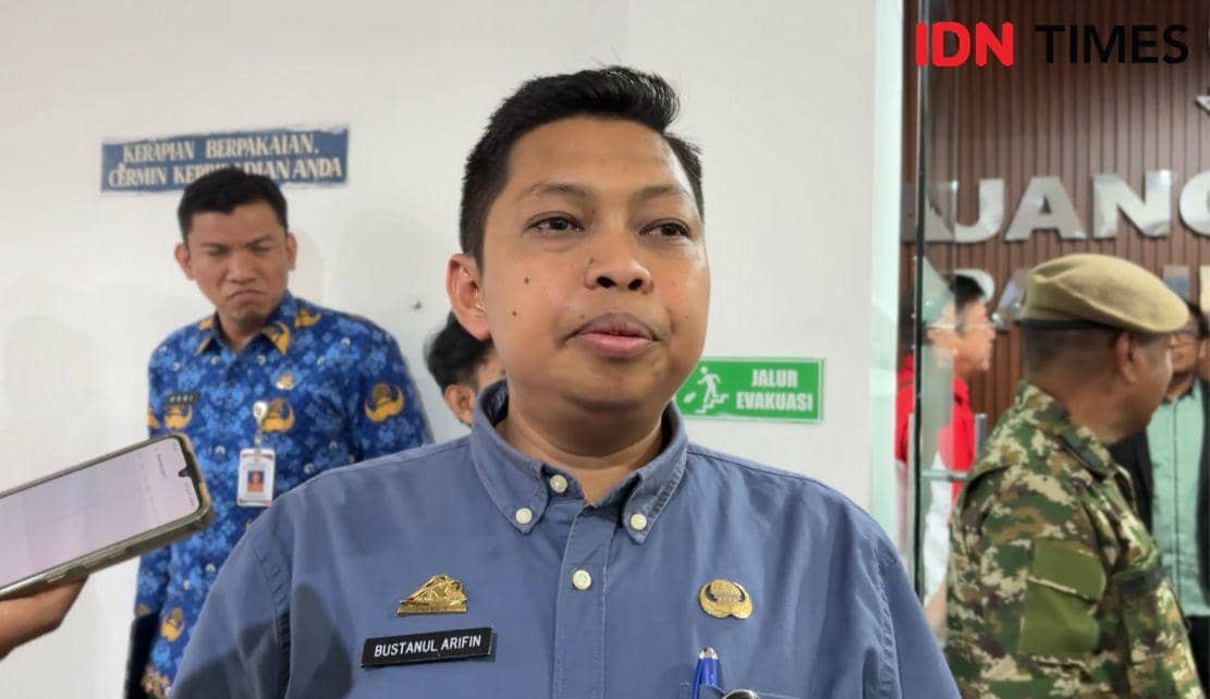 Seorang pejabat Kesbangpol Sulsel berbicara kepada media di gedung DPRD Sulsel dengan beberapa orang berdiri di latar belakang.