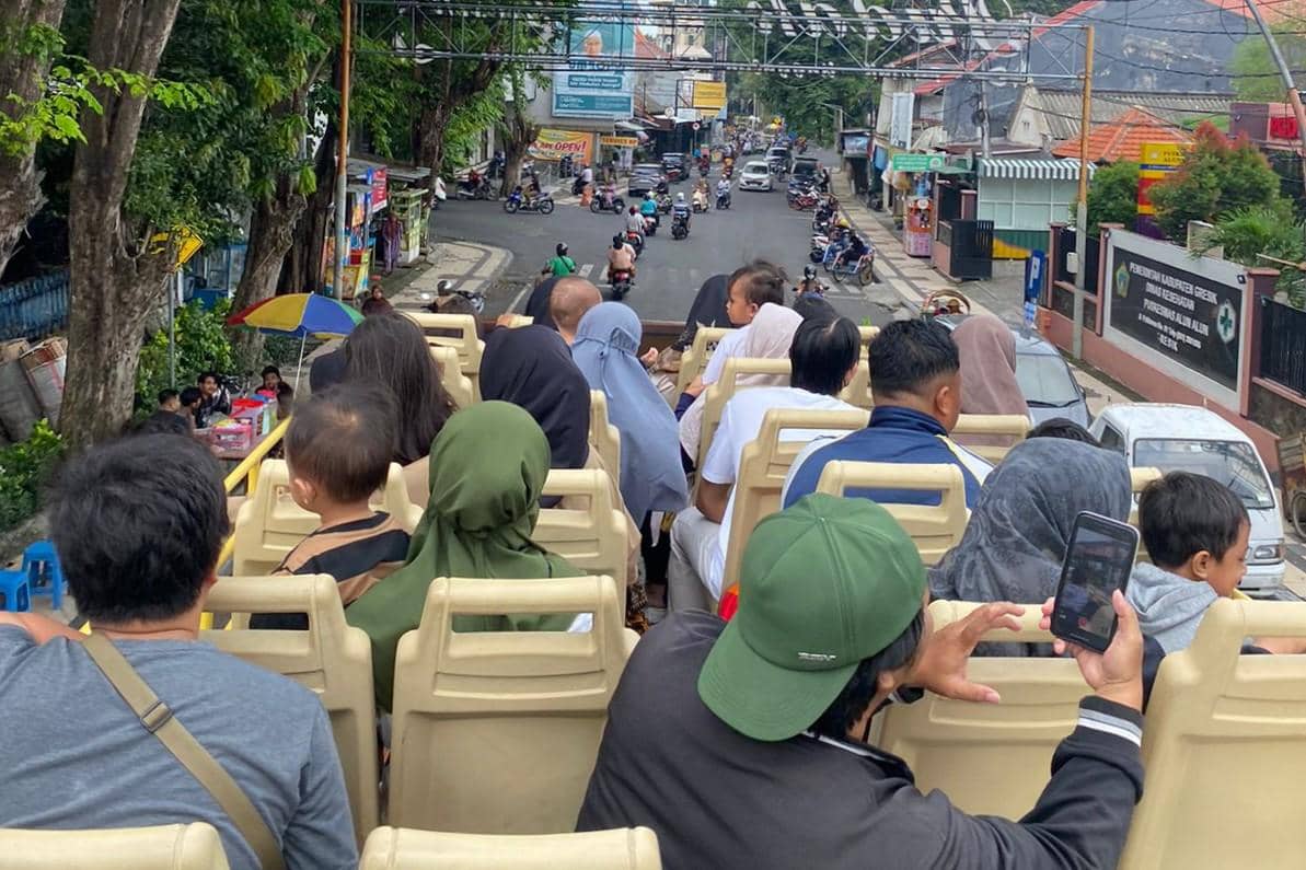 Wisatawan menikmati perjalanan menggunakan bus tingkat wisata di kawasan kota lama Gresik.