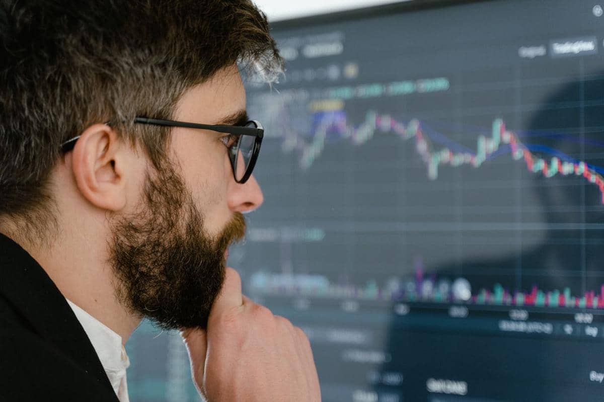 ilustrasi seorang pria yang fokus melihat layar yang menampilkan grafik saham