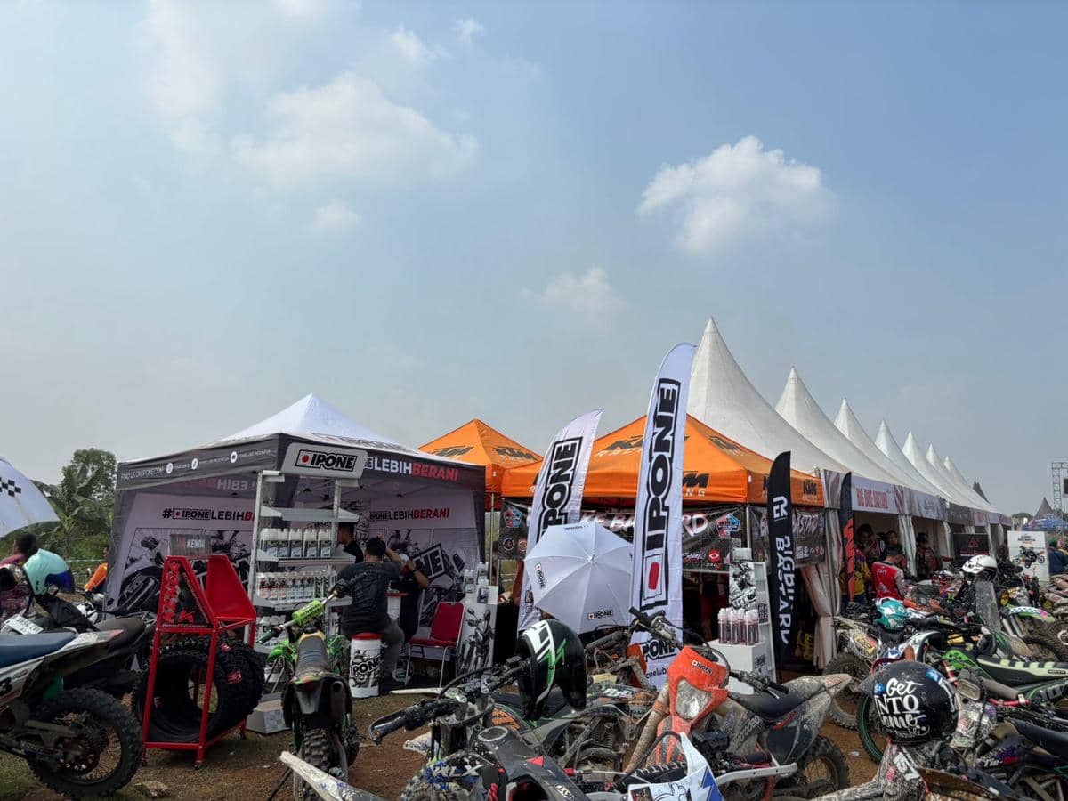 Deretan tenda dan motor trail di acara Bogor Hujan Trail 2026 dengan peserta dan pengunjung yang memadati area pameran.
