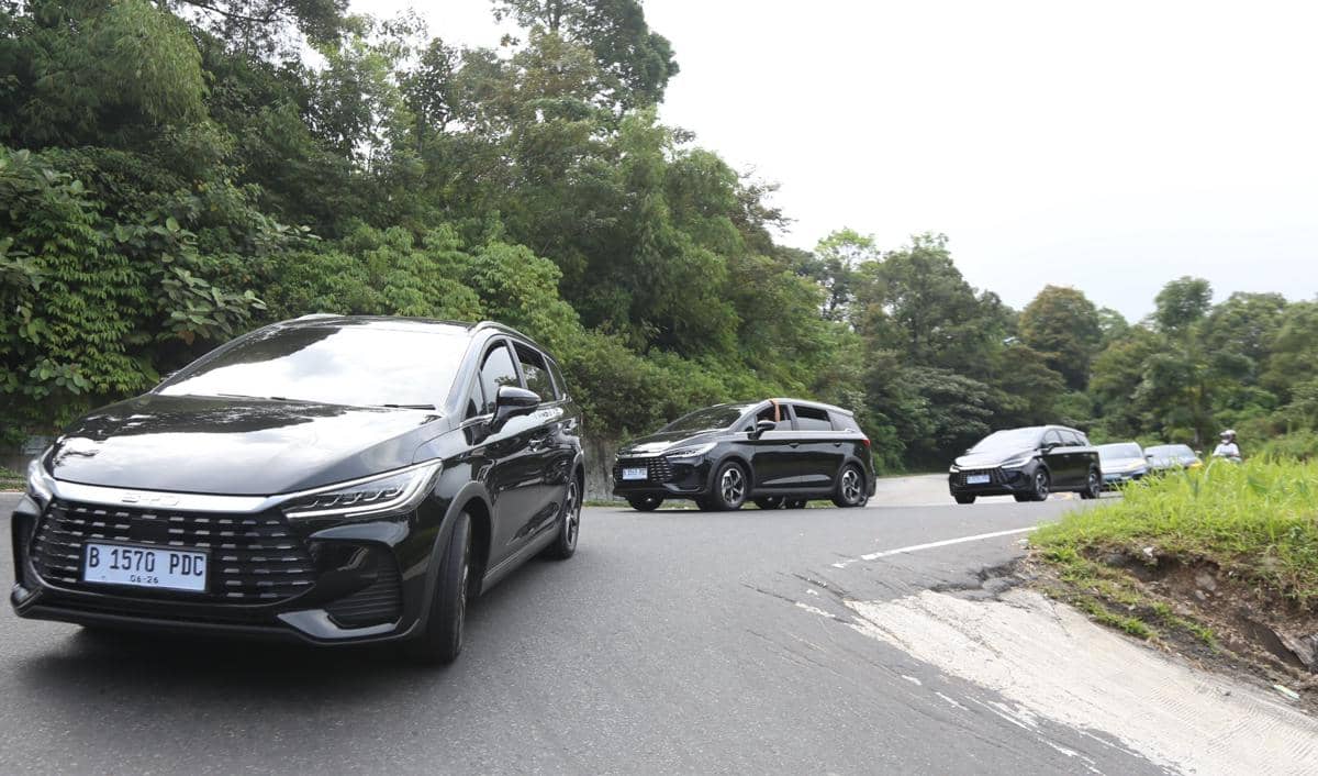Beberapa mobil BYD DM 1 berwarna hitam melaju di jalur tanjakan Berastagi, Sumatra Utara, dikelilingi pepohonan hijau.