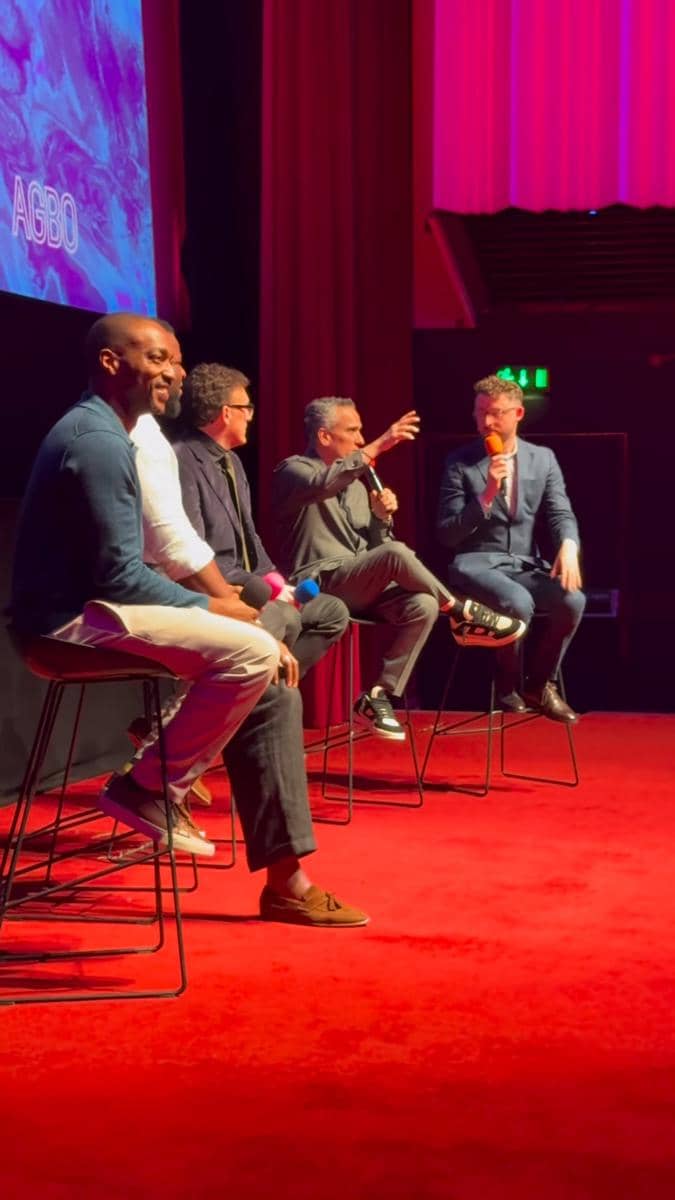 Beberapa orang duduk di atas panggung berkarpet merah saat diskusi panel di SXSW London 2026 dengan latar layar bertuliskan AGBO.