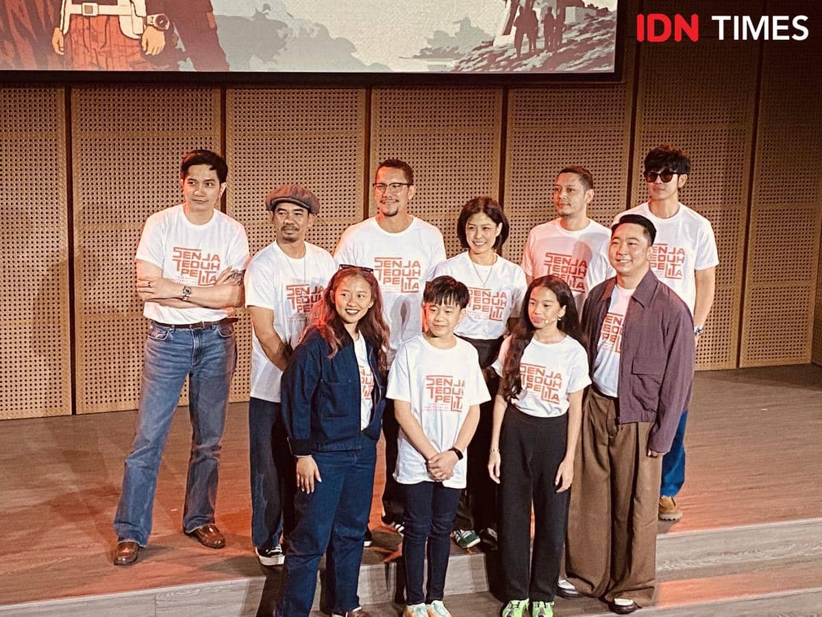 Para pemain dan kru pertunjukan musikal Senja Teduh Pelita berpose bersama saat konferensi pers di atas panggung dengan latar kayu.