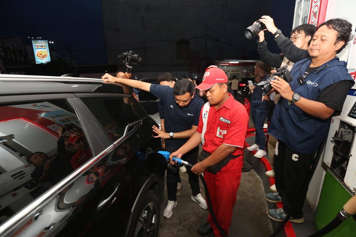 Petugas SPBU mengisi bahan bakar mobil BYD DM 1 berwarna hitam saat pengujian di Berastagi, Sumatra Utara, disaksikan beberapa orang dan fotografer.
