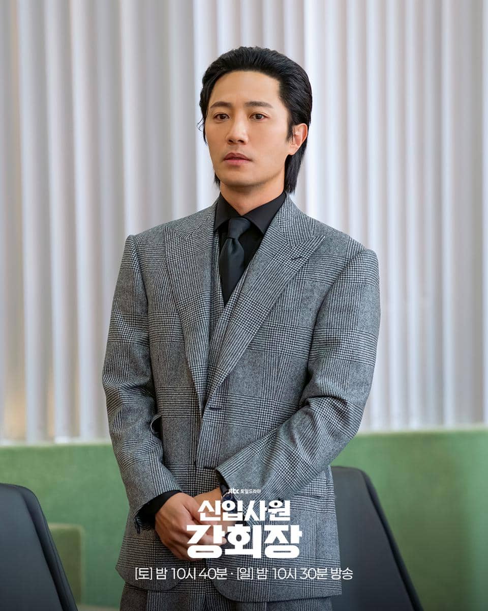 Seorang aktor mengenakan setelan jas abu-abu dengan kemeja dan dasi hitam dalam cuplikan drama Reborn Rookie.
