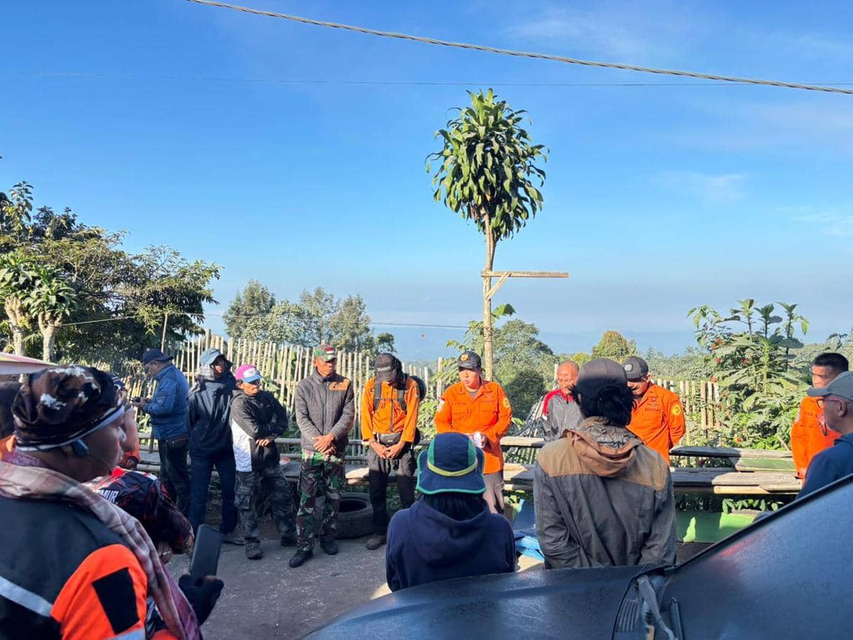 Tim SAR Surabaya mengenakan seragam oranye berdiri bersama warga saat proses evakuasi pendaki di kawasan Gunung Semeru.
