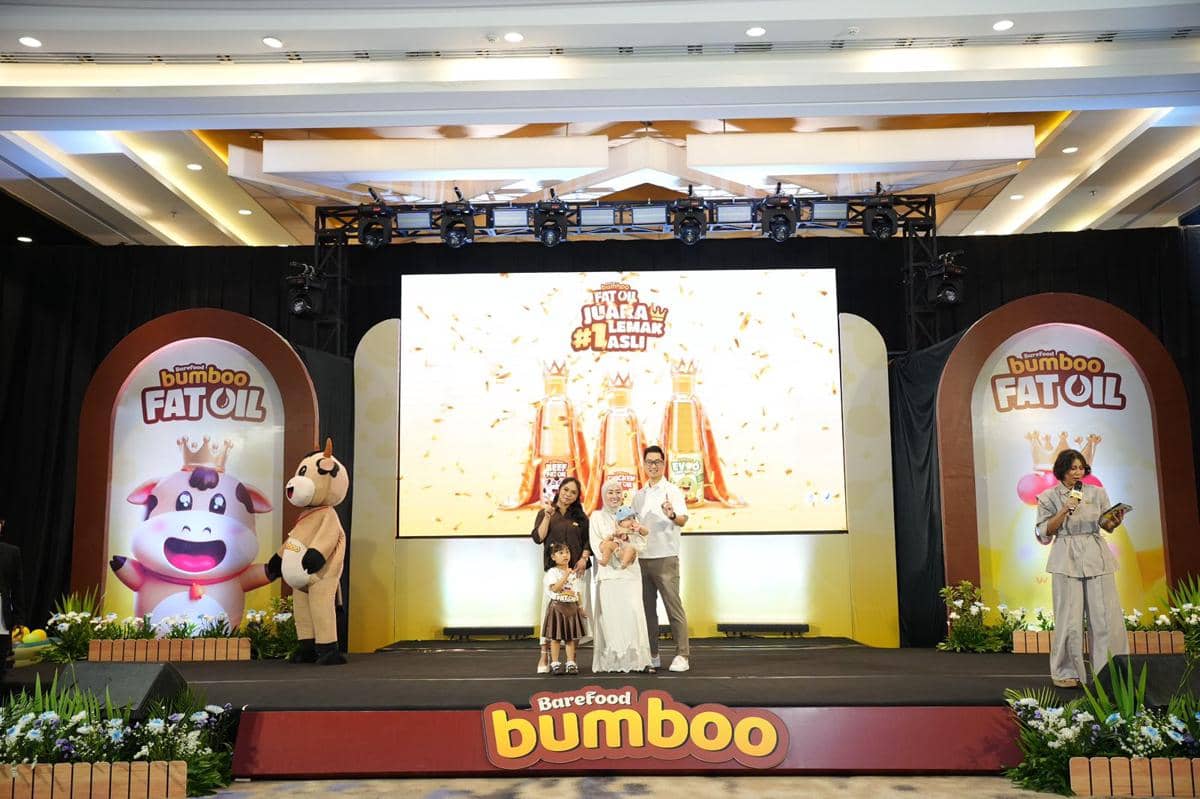 Acara peluncuran Bumboo Fat Oil oleh Barefood Indonesia dengan panggung berdekorasi cerah dan karakter maskot sapi di sisi panggung.
