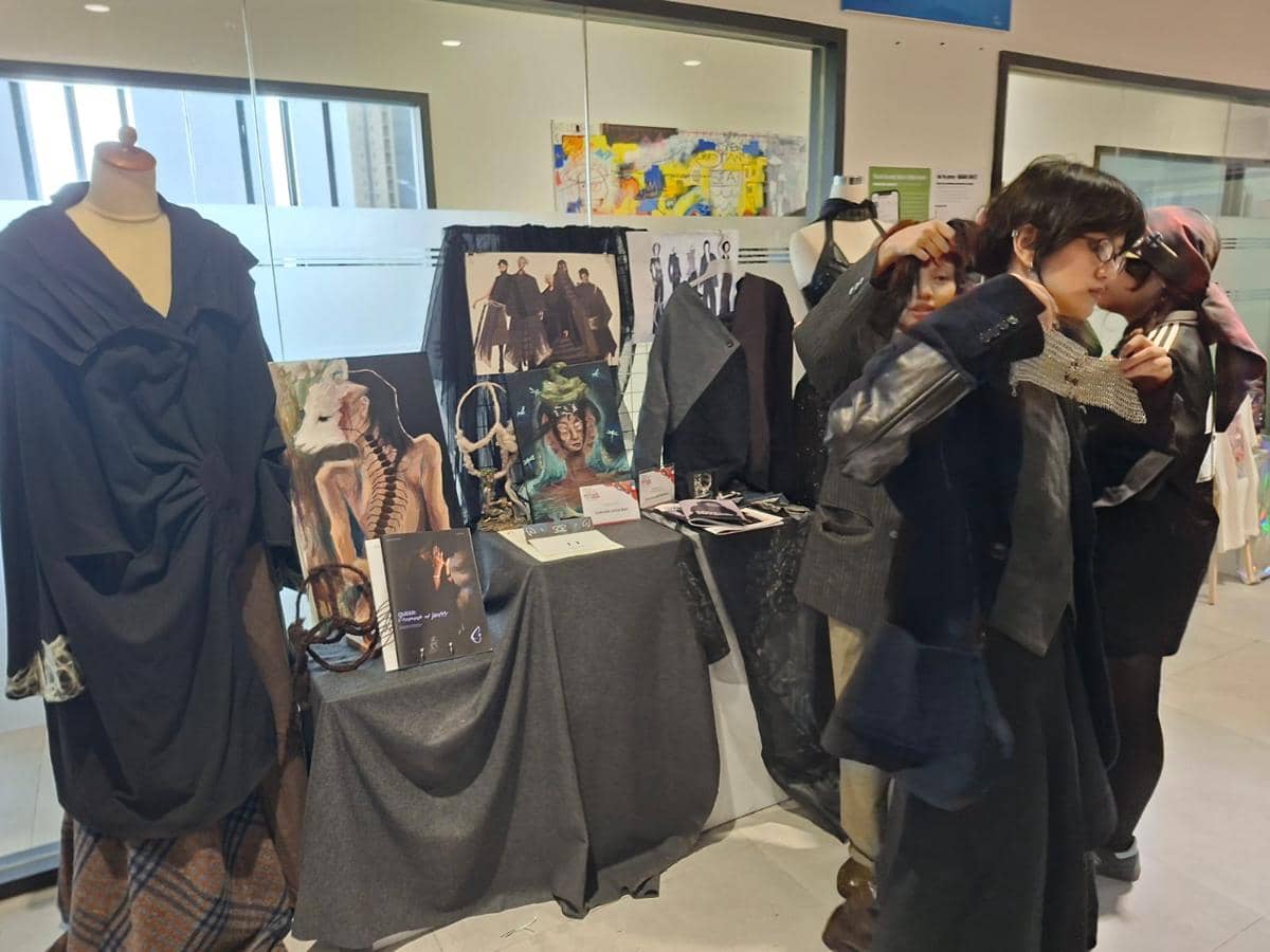 Siswa UIC Tangerang menyiapkan karya busana dan seni rupa di meja pameran dengan berbagai lukisan serta desain kostum kreatif.