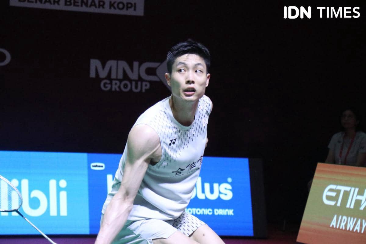 Seorang pebulu tangkis mengenakan seragam putih sedang bersiap memukul shuttlecock di lapangan turnamen Indonesia Open 2026.