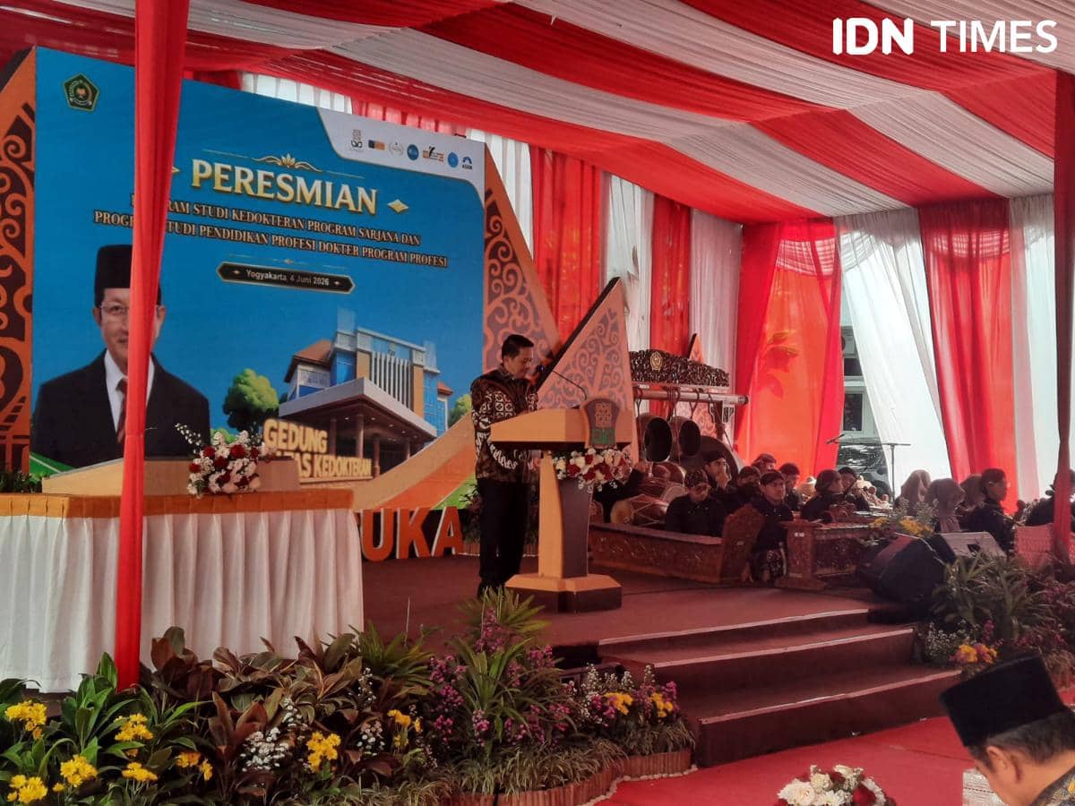 Seorang pria berpidato di podium pada acara peresmian Program Studi Kedokteran di UIN Sunan Kalijaga Yogyakarta dengan dekorasi merah putih.